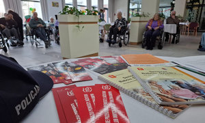 ulotki leżące na stole, w tle seniorzy