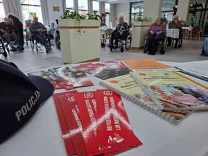 ulotki leżące na stole, w tle seniorzy