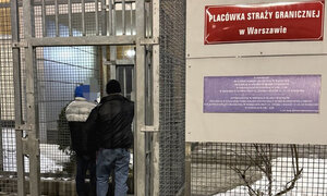 zatrzymany mężczyzna w asyście nieumundurowanego policjanta przy wejściu do Placówki Straży Granicznej w Warszawie
