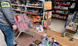 nieumundurowany policjant z opaską odblaskową z napisem POLICJA założoną na ramieniu, w tle widoczny zabezpieczony towar