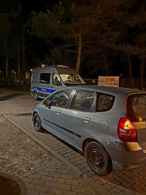auto zatrzymane do kontroli drogowej, w tle policyjny oznakowany radiowóz