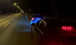 nieoznakowany radiowóz policji z napisem POLICJA, a przed nim auto zatrzymane do kontroli drogowej