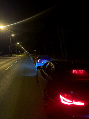 nieoznakowany radiowóz policji z napisem POLICJA, a przed nim auto zatrzymane do kontroli drogowej