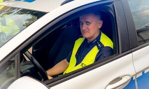 mł. asp. Kamil Niedziałek siedzący w radiowozie oznakowanym