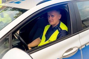 mł. asp. Kamil Niedziałek siedzący w radiowozie oznakowanym