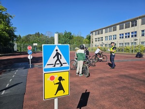 policjant rozmawiający z uczniami, w tle strażniczka miejska