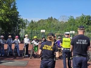 policjant rozmawiający z uczniami, w tle strażniczka miejska