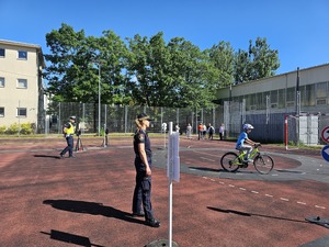 policjant rozmawiający z uczniami, w tle strażniczka miejska