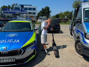 kierujący hulajnogą elektryczną stojący przy policyjnym oznakowanym radiowozie