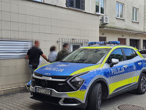 zatrzymana kobieta w trakcie doprowadzania do policyjnego radiowozu, przez dwóch nieumundurowanych policjantów