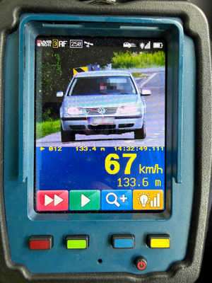 zdjęcie z urządzeniem do pomiaru prędkości, widać na nim pojazd marki VW koloru szarego oraz zmierzoną prędkość 67 km/h