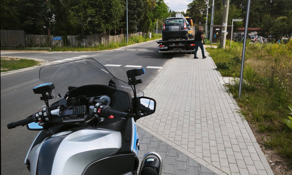 policyjny oznakowany motocykl, w tle auto na lawecie