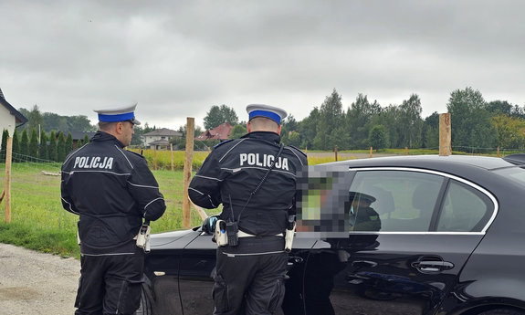 dwaj umundurowani policjanci drogówki kontrolujący kierującego pojazdem
