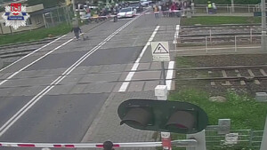 mężczyzna prowadzący hulajnogę elektryczną, przechodzący przez przejazd kolejowo-drogowy, kiedy zapory były opuszczone