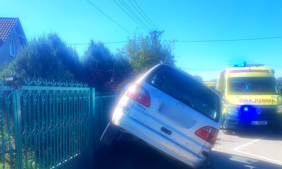 auto, którego kierujący uderzył w ogrodzenie. W tle karetka pogotowia
