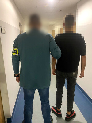 zatrzymany mężczyzna w asyście nieumundurowanego policjanta, zdjęcie wykonane na korytarzu