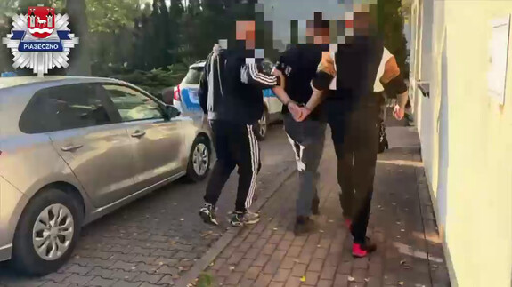 zatrzymany mężczyzna prowadzony przez dwóch nieumundurowanych policjantów
